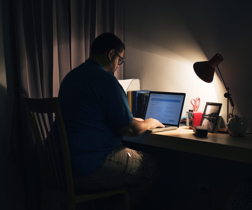 Man working in a dark home office with a laptop